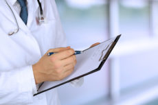 young medical doctor with a stethoscope around his neck holding a black folder