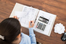 39435815 - businesswoman calculating tax at desk with calculator in office